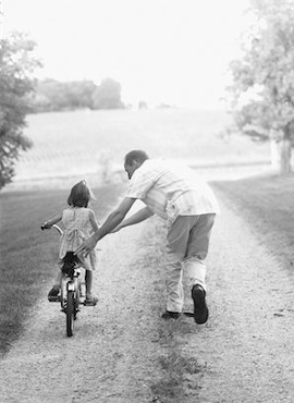 Papá enseña hija a andar en bici